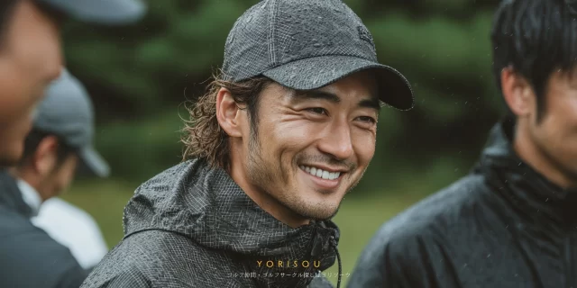 海老名市下今泉在住の50代男性ゴルファーが、ゴルフウェア姿でバストアップになり、雨天ラウンド後でも穏やかに微笑んでいる様子。周囲には同伴者の姿がぼんやり映る。