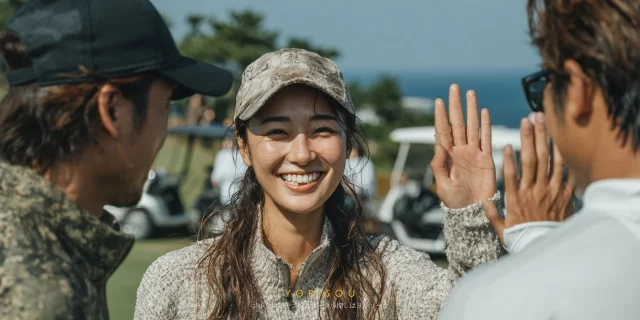 瀬戸市品野町でゴルフ仲間とハイタッチする30代女性ゴルファーが、ゴルフウェア姿でバストアップに写る交流シーン