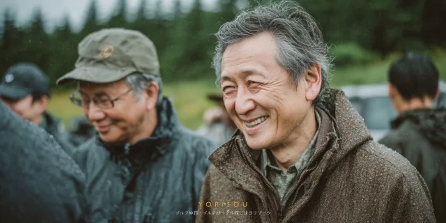 千葉市若葉区大宮町周辺のゴルフ場で、ゴルフウェアを着た60代男性ゴルファーがバストアップで穏やかに笑顔を見せている様子、雨上がりのコンディションの中で同伴者と会話を楽しむ千葉市らしい落ち着いたラウンド風景