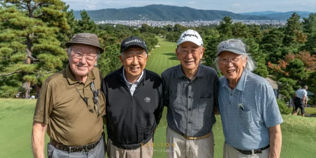 京都市山科区方面のゴルフ場で、60代〜70代の男性ゴルファー4人がゴルフウェア姿で並び、山並みを背景にバストアップで笑顔を見せている様子