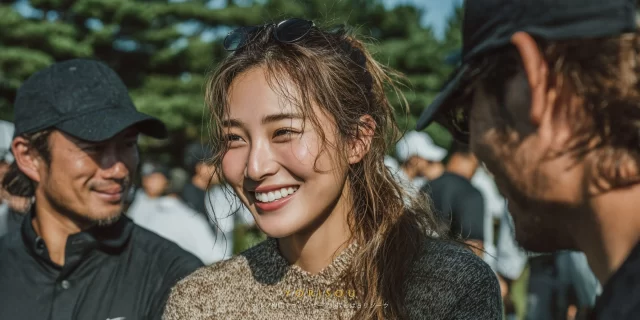 那覇市真嘉比エリアのゴルフ場で、30代女性ゴルファーがゴルフウェア姿で仲間と談笑しながら自然な笑顔を見せるバストアップ写真